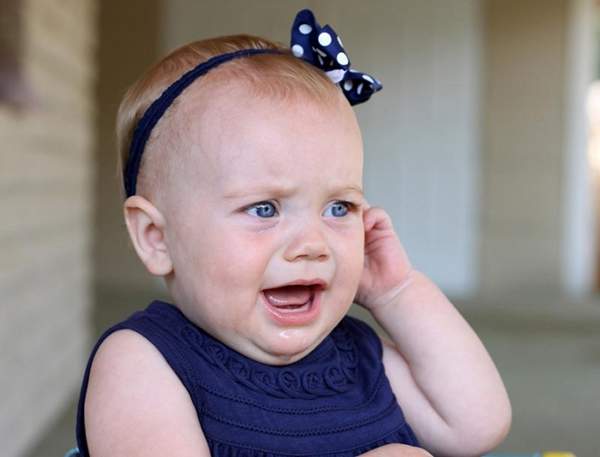 Девочка держится за больное ухо Девочка держится за больное ухо